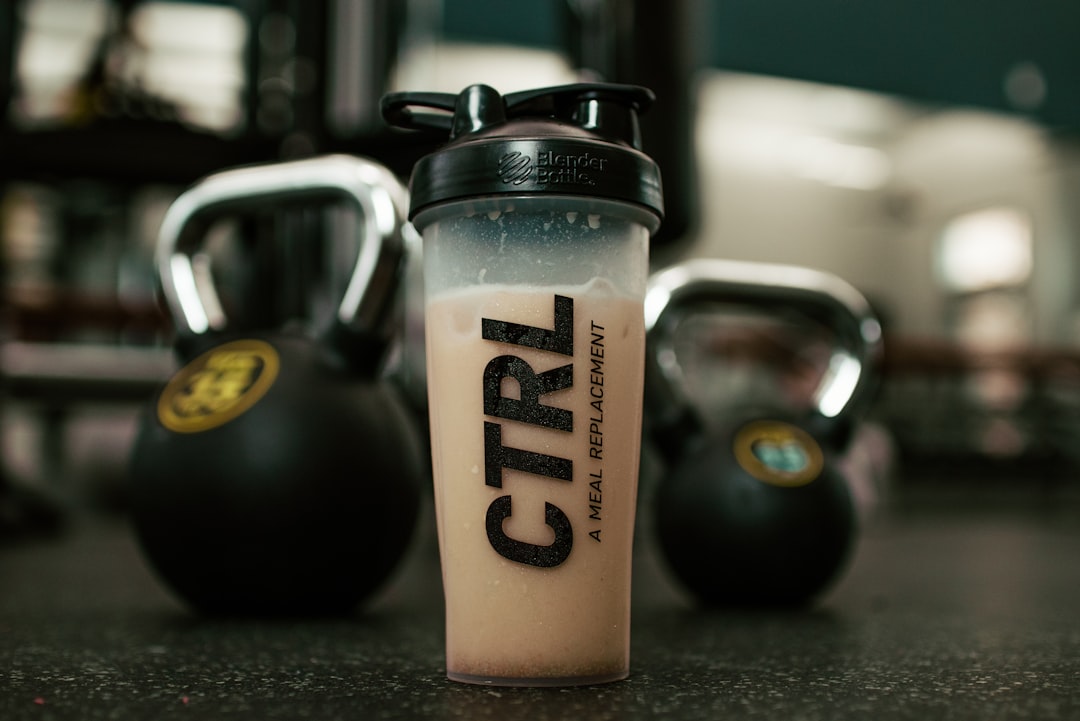 Protein shake in a shaker bottle beside kettlebells