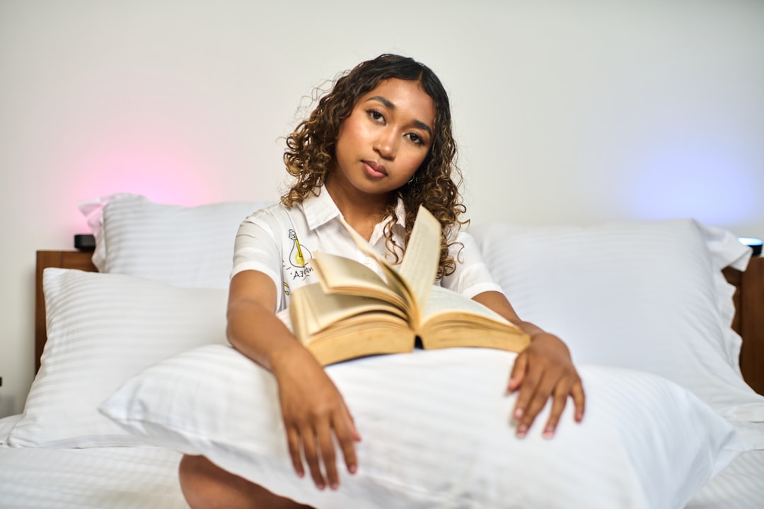 Person relaxing with a book on pillows before bed