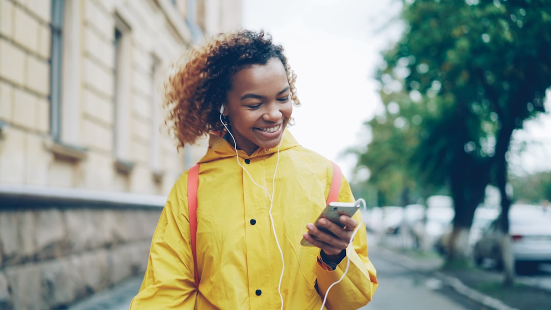 Smiling woman in a yellow jacket wearing earbuds before heading out
