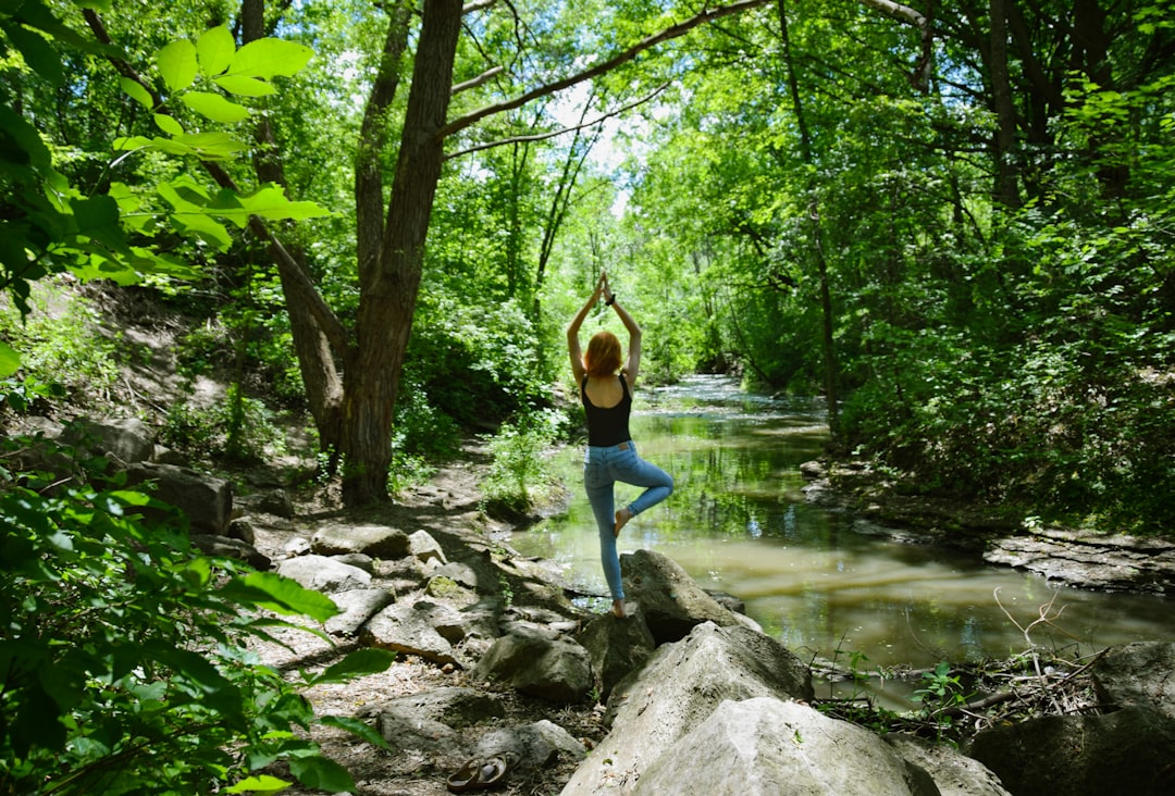 Woman holding tree pose outdoors near a river