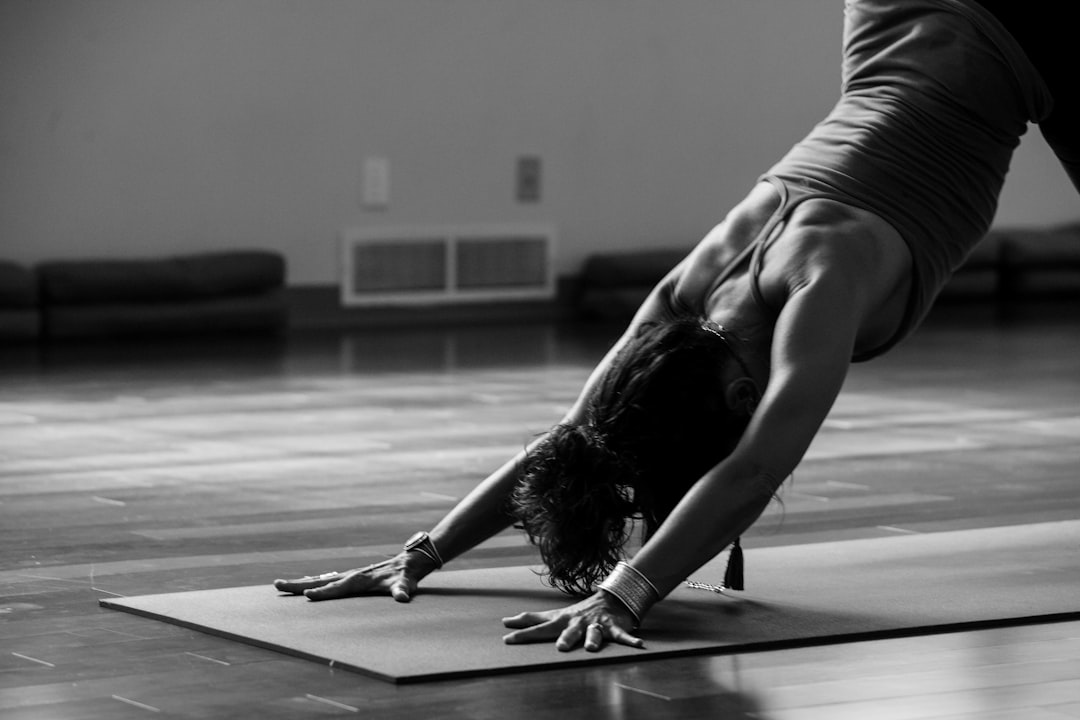 Woman holding downward dog pose on a yoga mat in a studio