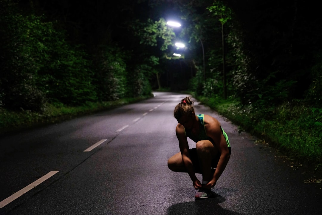 Runner in bright athletic wear illuminated on a dark road