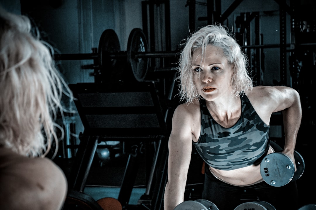 Older woman with white hair lifting dumbbells in a gym