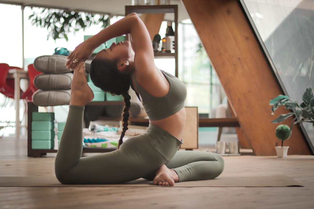 Woman practicing a backbend pose on a yoga mat indoors