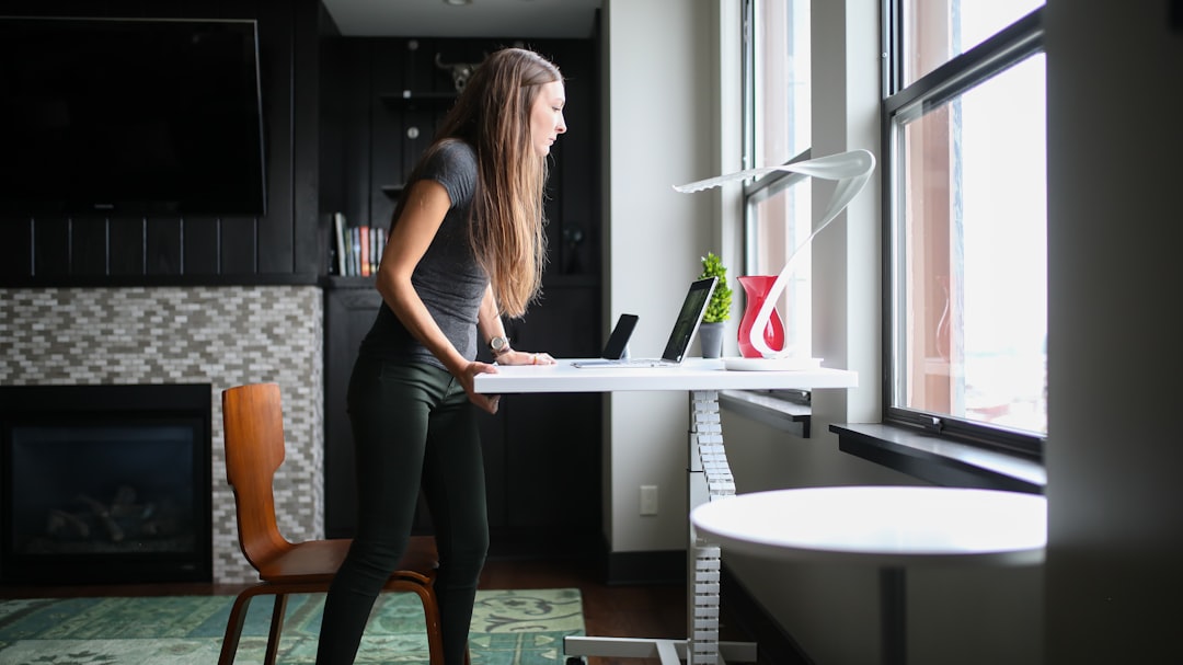 Woman working at a height-adjustable desk with a laptop