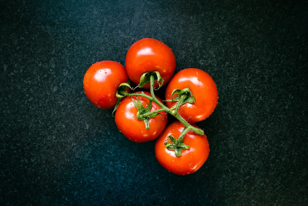 Fresh ripe tomatoes with basil leaves on a wooden surface