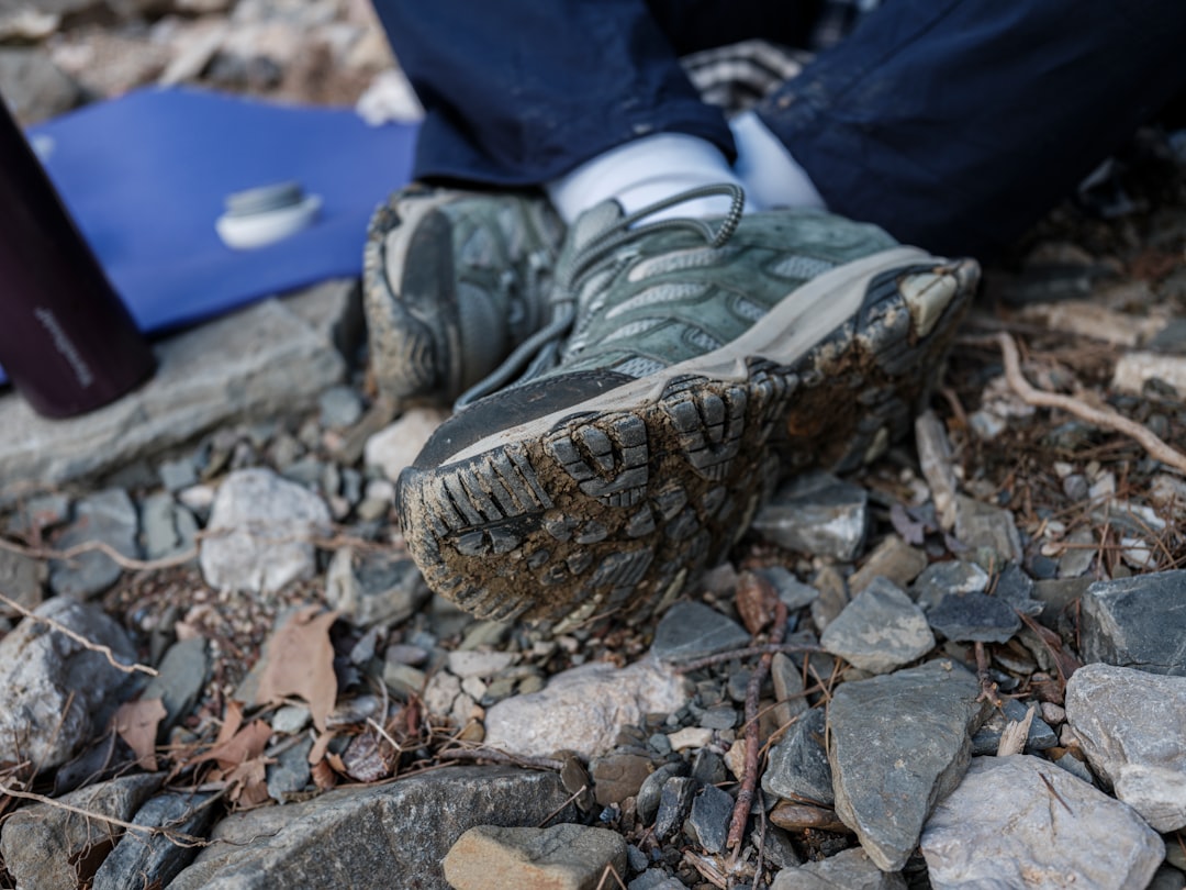 Muddy waterproof hiking boots resting on rocky trail