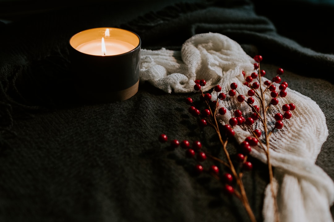 Lit candle with winter berries glowing in a dim evening room