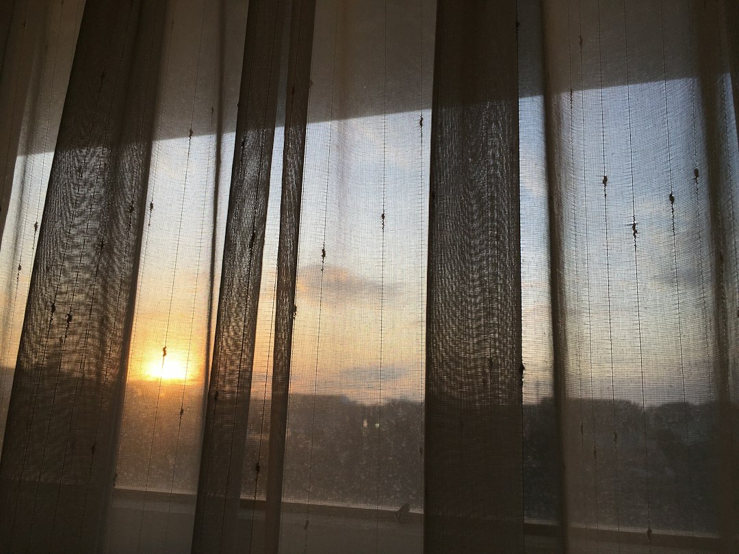 Golden sunrise light streaming through sheer curtains
