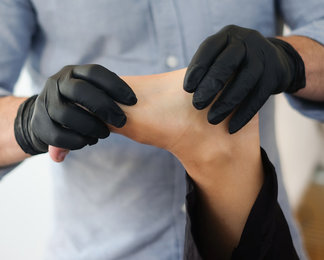 Gloved physical therapist treating a patient's ankle in a clinic