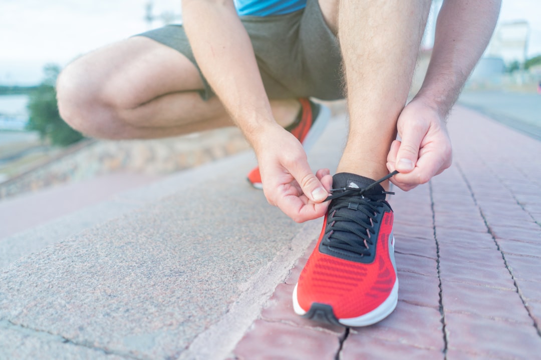 Athlete lacing up red running shoes on a brick sidewalk