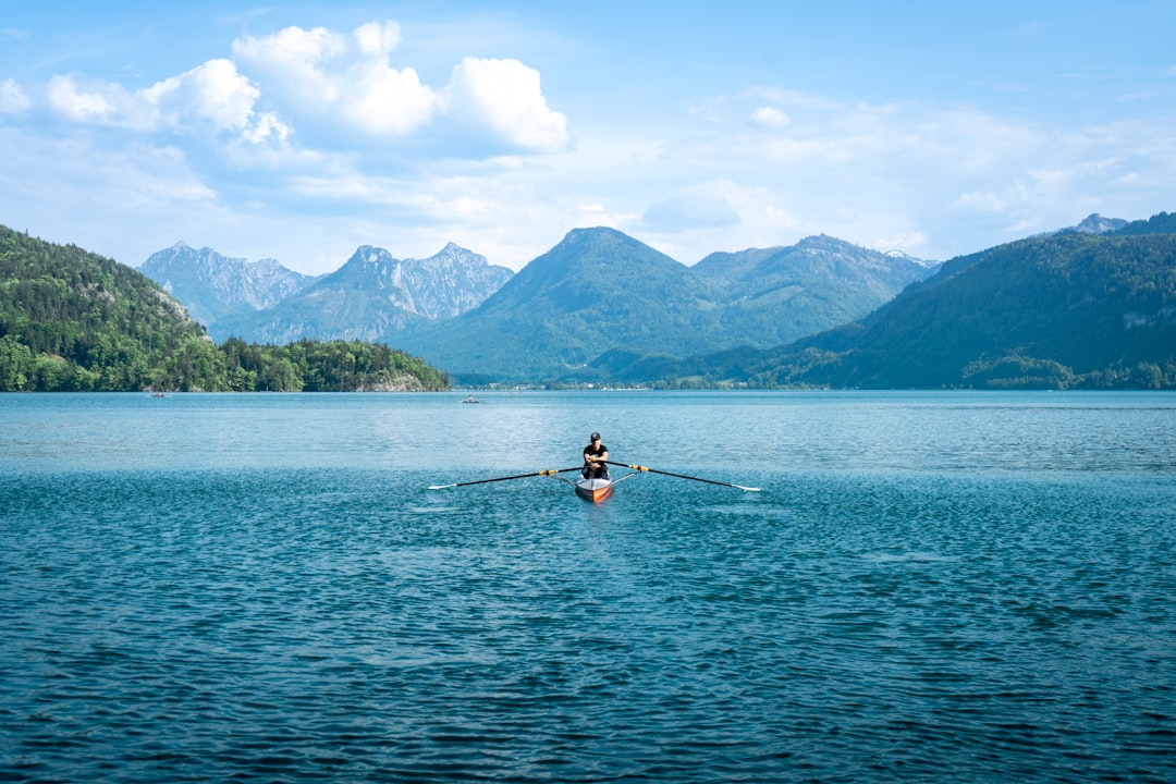 Rower gliding across a calm mountain lake at midday