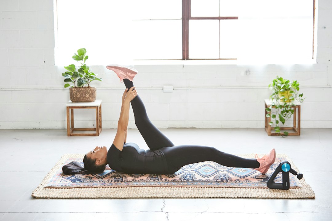 Woman stretching on a mat beside a wheeled mobility roller