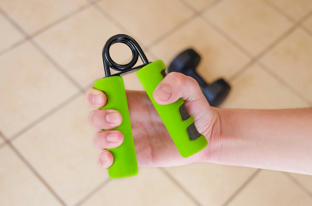 A hand squeezing a spring-loaded adjustable grip strengthener