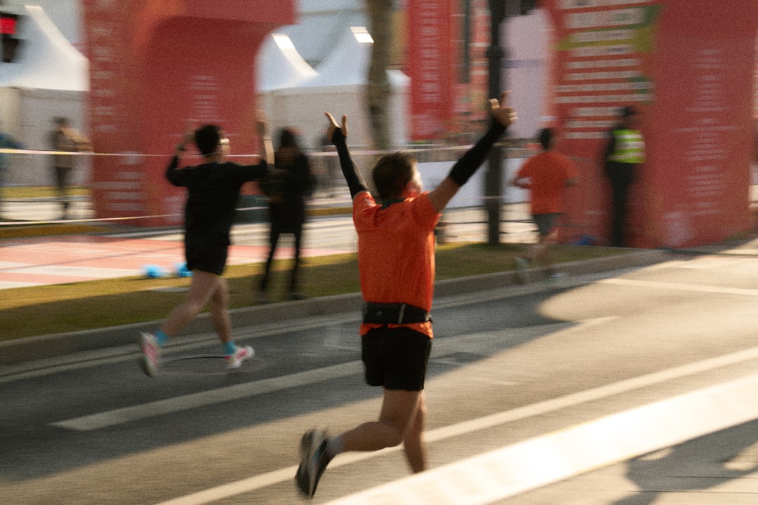 Runner crossing a marathon finish line with arms raised in celebration