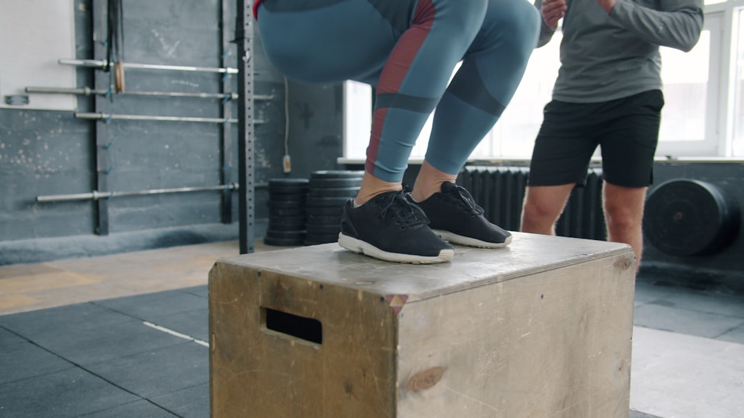 Adult performing an explosive plyometric box jump in a gym