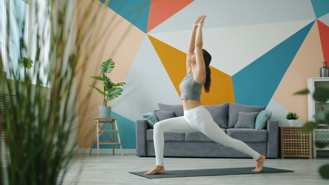 Woman holding a yoga warrior pose in a bright living room