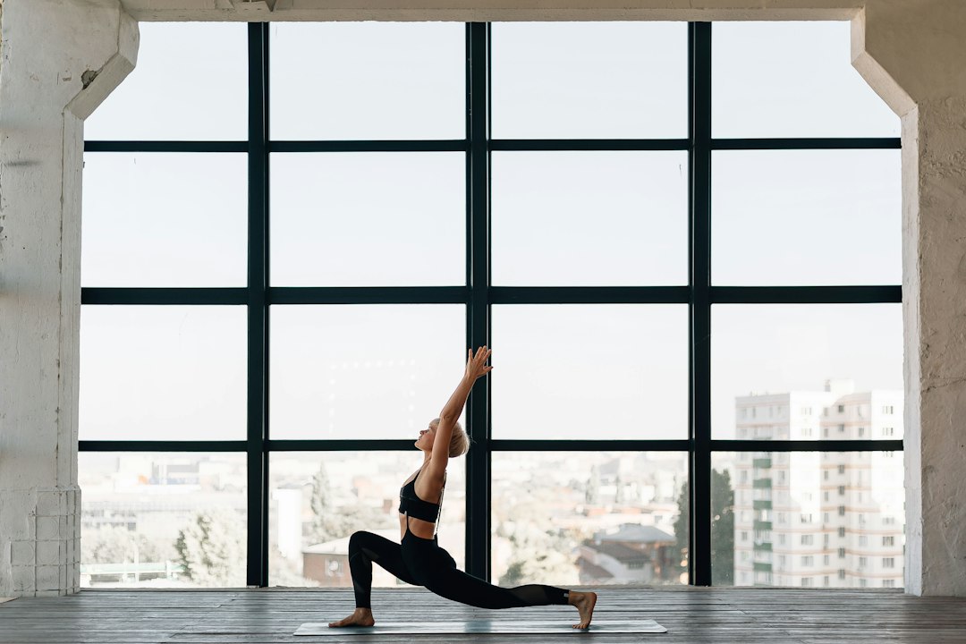 Woman holding a steady yoga warrior pose in a bright studio