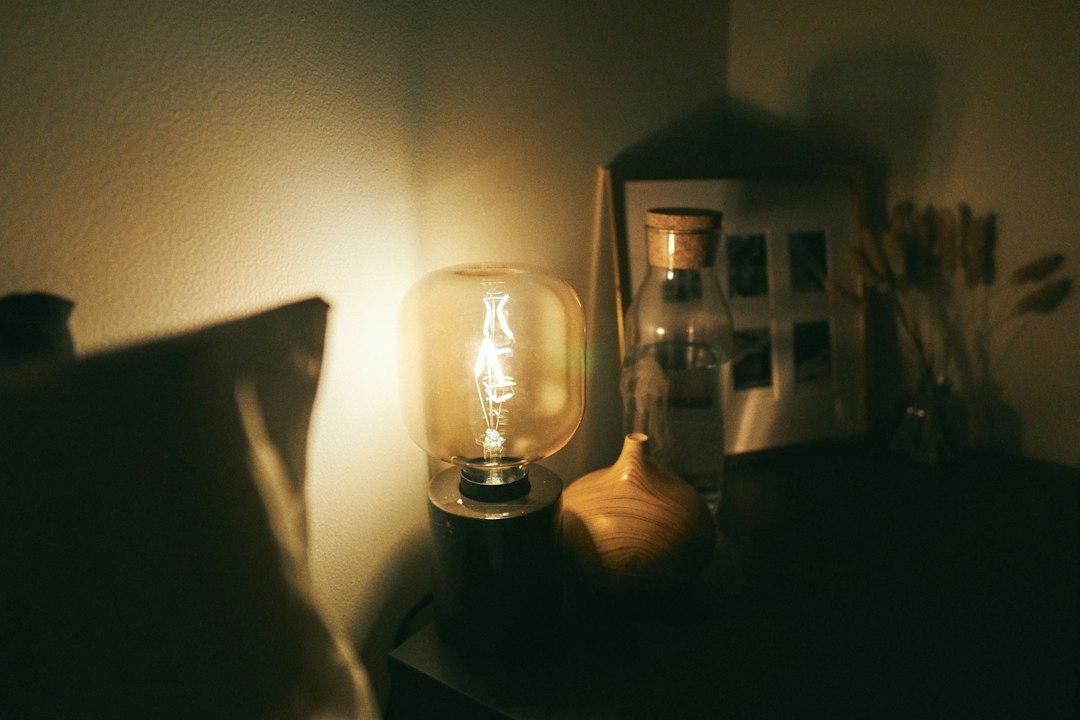 Warm glowing lamp on a nightstand beside a bed, evening in the bedroom