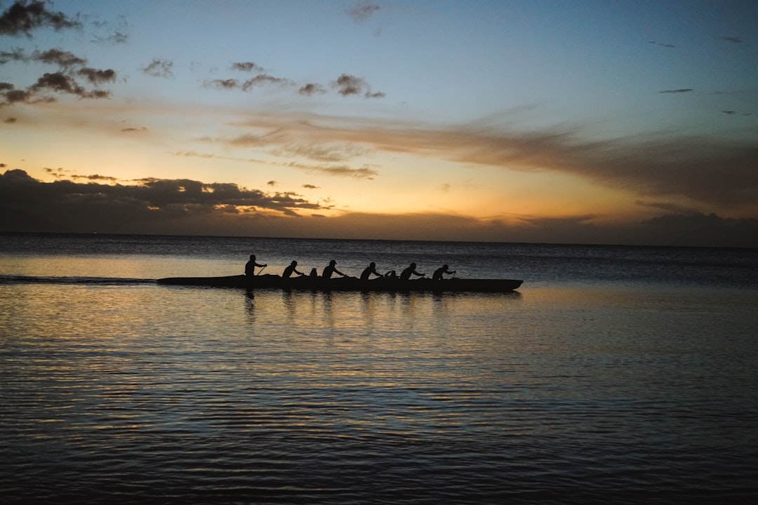 Rowing crew silhouetted against a golden sunset on the water