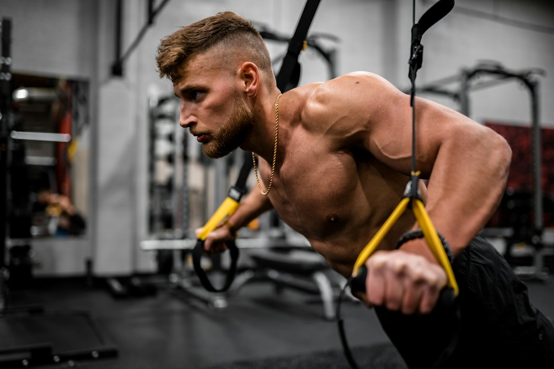 Muscular man exercising with a suspension trainer in a modern gym