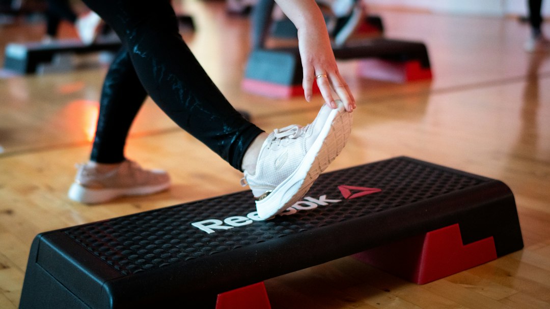 Sneaker stepping onto a black aerobic step platform in a gym studio
