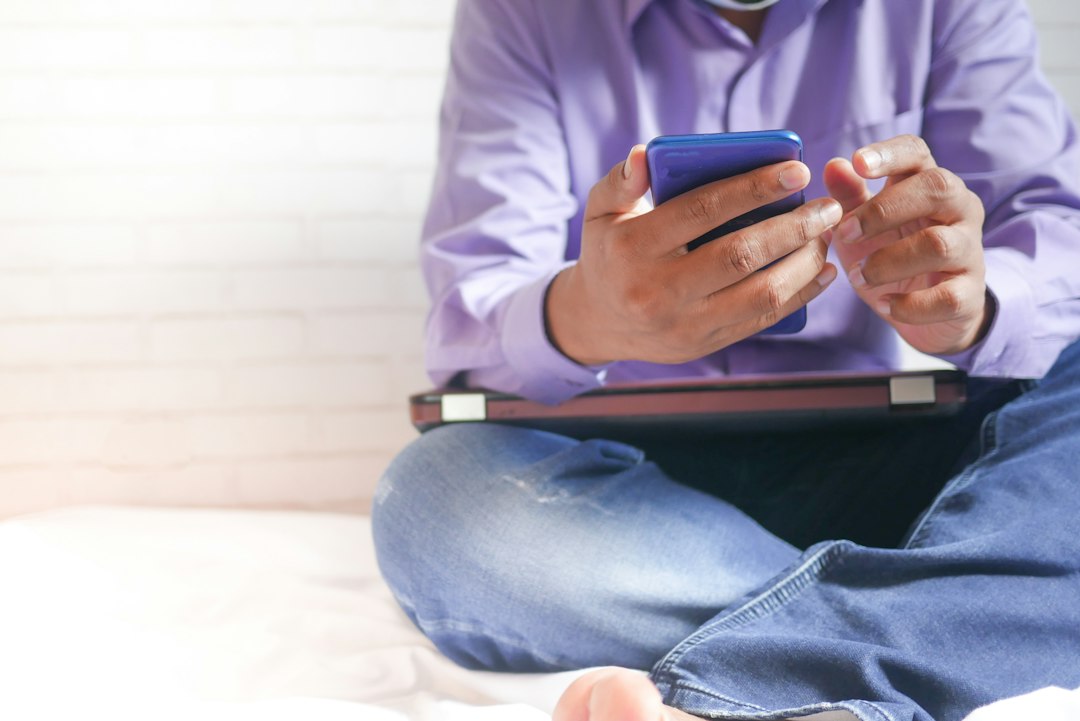 Person sitting on a bed using a smartphone in the morning