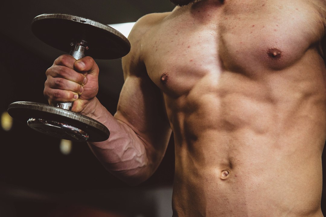 A lifter's forearm and hand gripping a dumbbell under heavy load