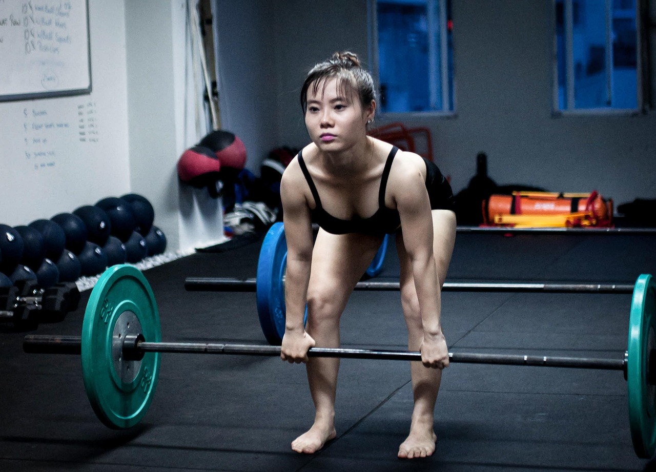 Woman setting up for a barbell deadlift in a strength training gym