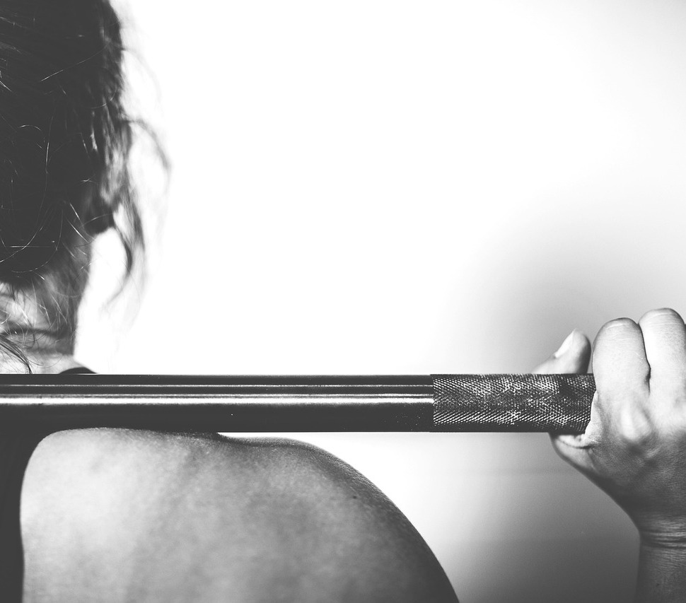 Woman gripping a loaded barbell across her upper back before a heavy squat
