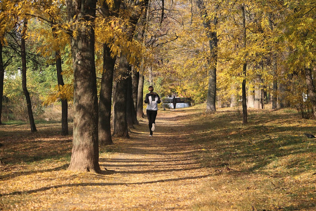 A woman running a leaf-covered path in autumn light