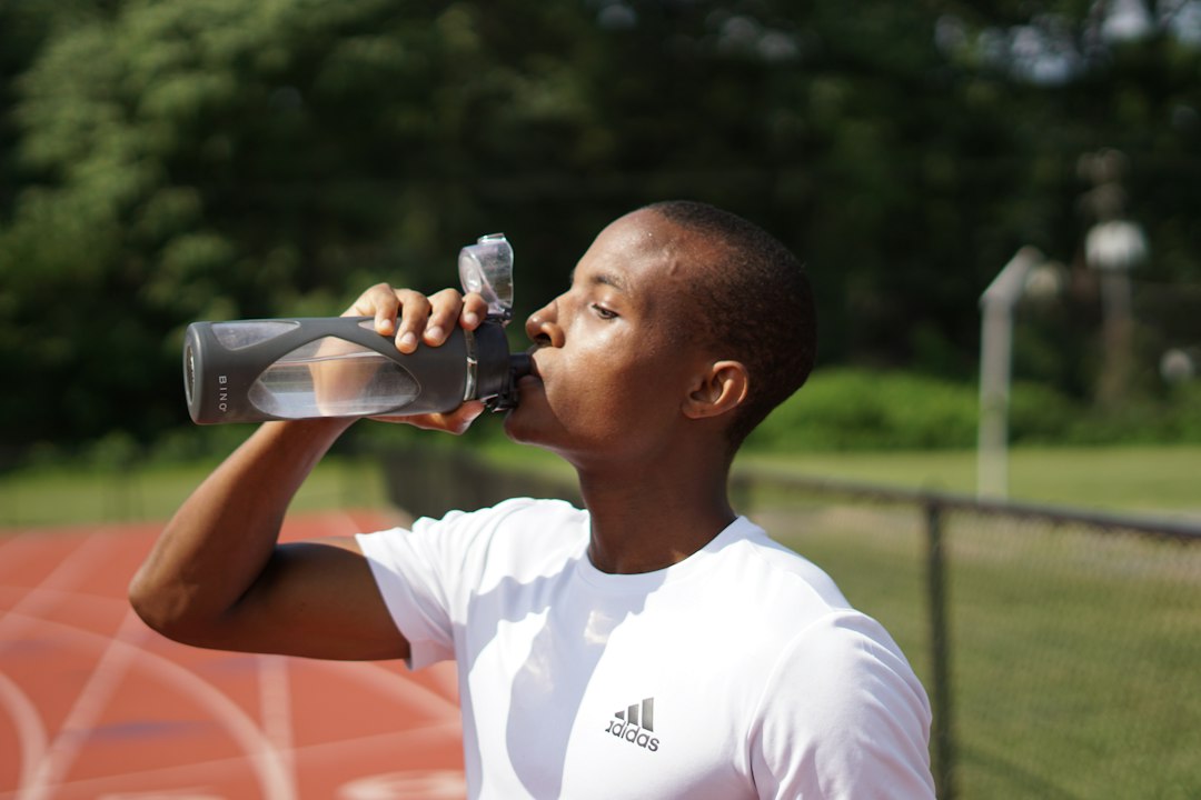 Runner drinking from a water bottle on the track