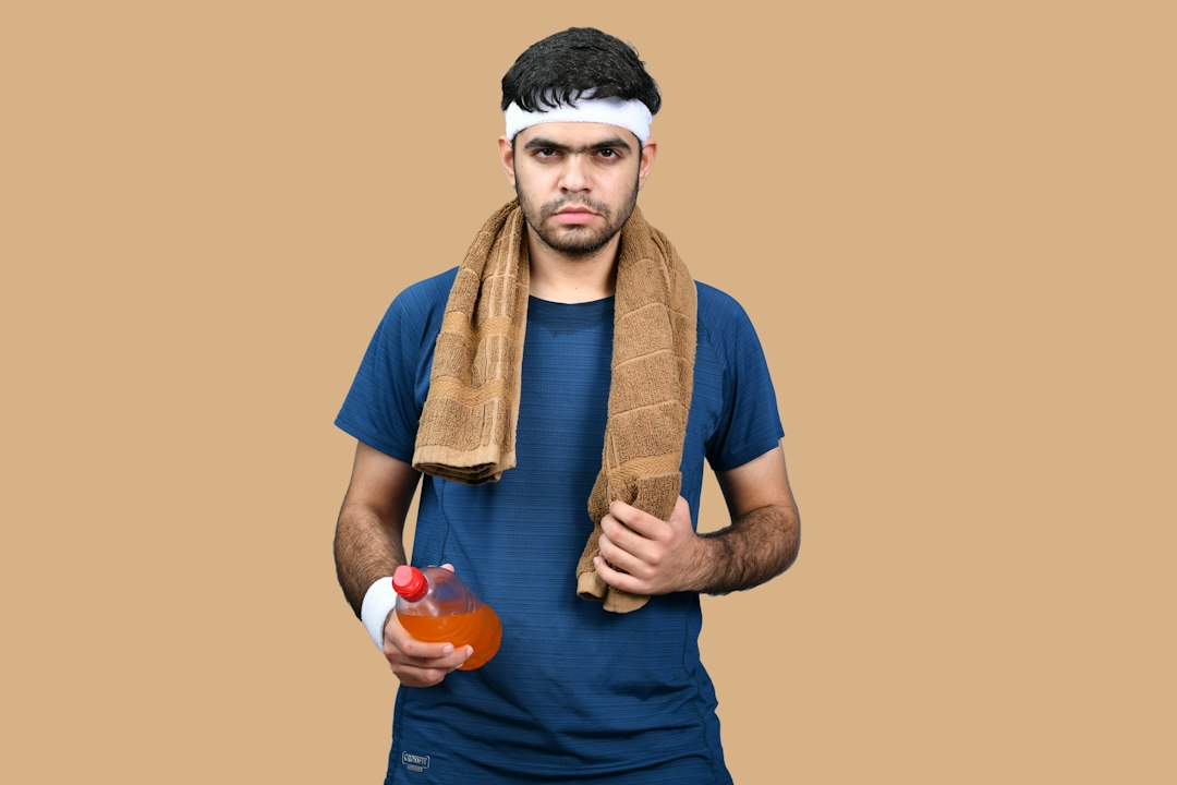 Athlete with a towel around his neck holding a sports drink