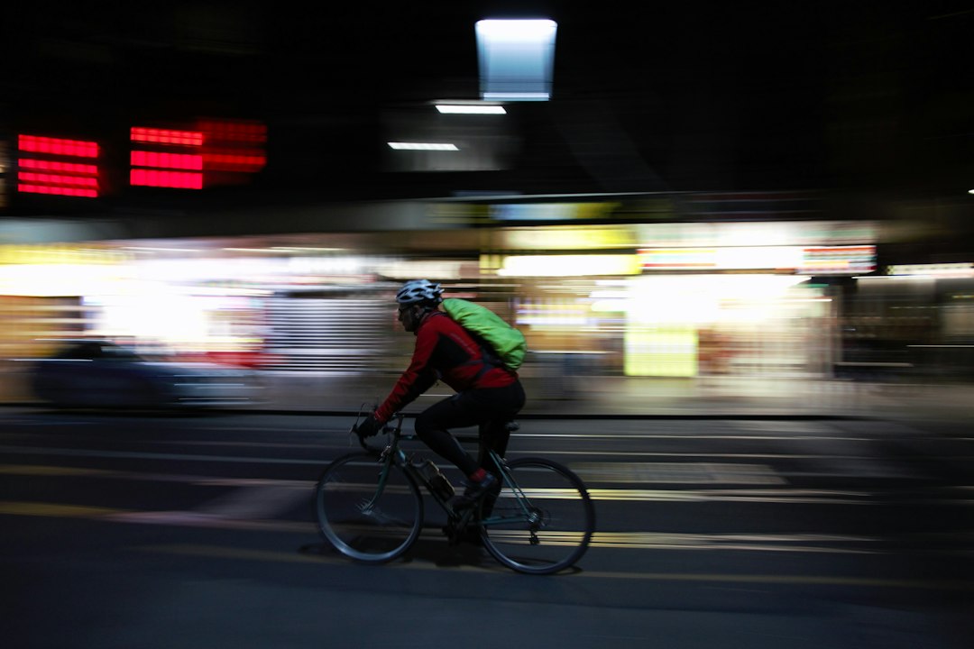A cyclist in motion at night with streaks of red and white traffic light trails
