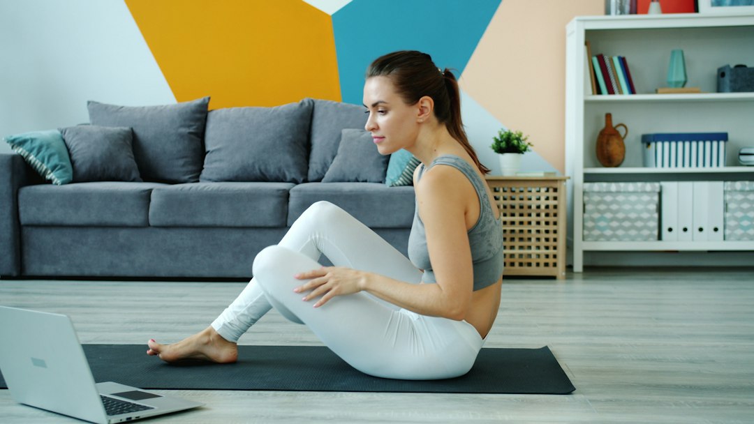 Woman following a workout session on a laptop at home on a yoga mat