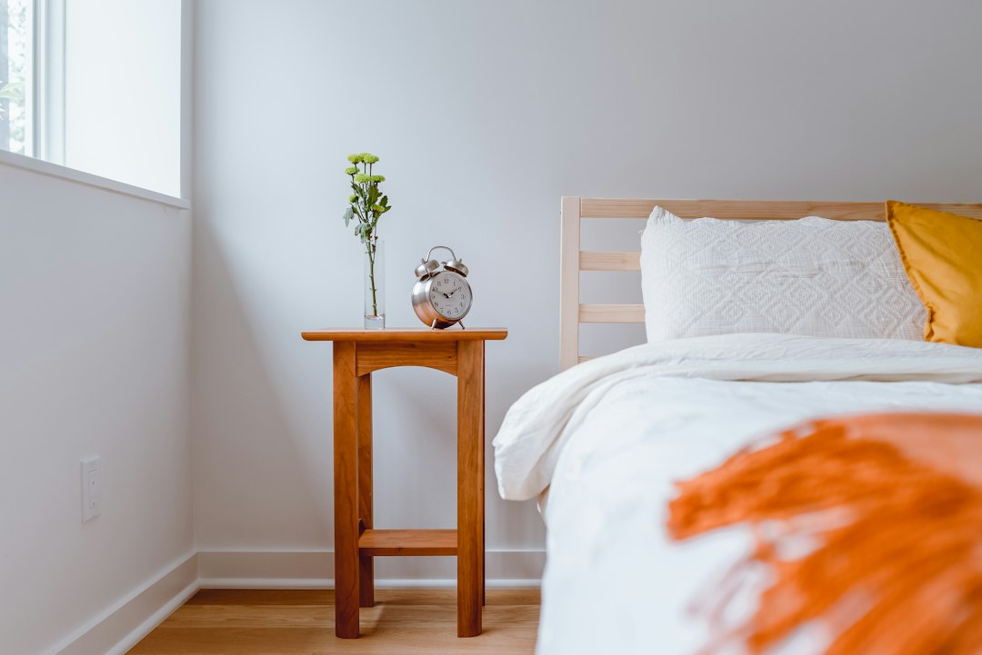 A tidy bedroom corner with a wooden nightstand beside the bed