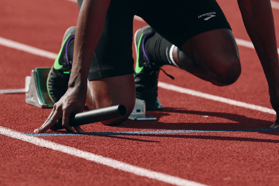 Athlete in a crouch start position on a running track, gripping the starting blocks