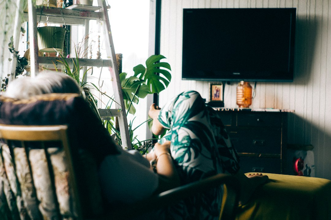 A woman relaxing in an armchair in a dim living room near a television