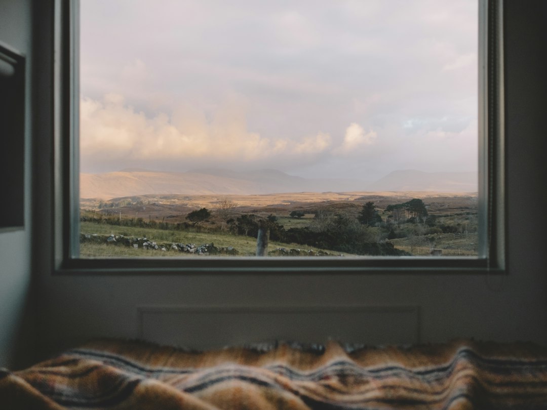 grey misty morning seen through a window with a plaid blanket
