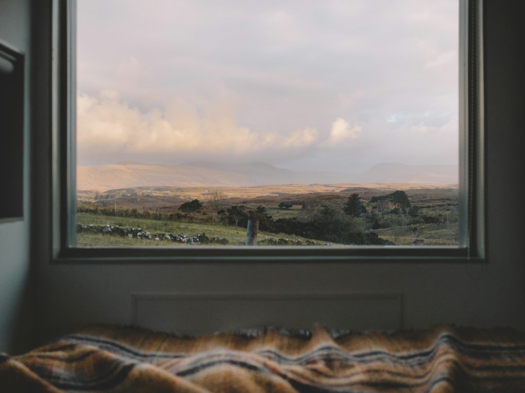 Dawn light glowing through a bedroom window over misty morning hills