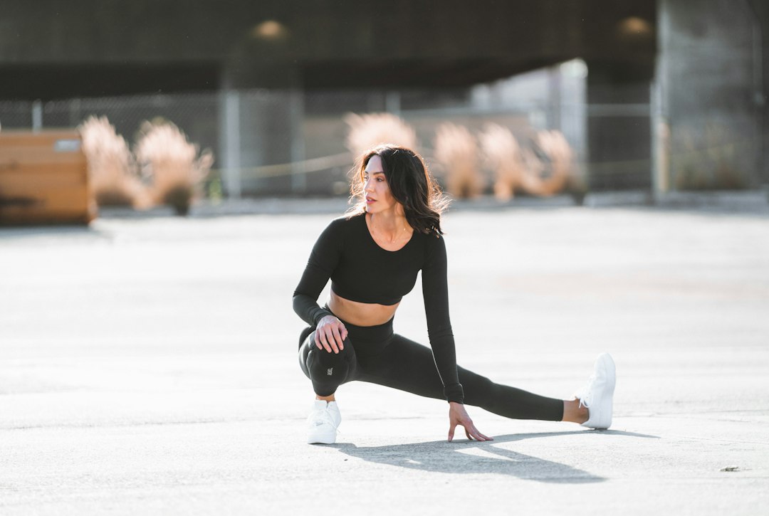 Woman performing a deep side lunge stretch on an urban concrete plaza