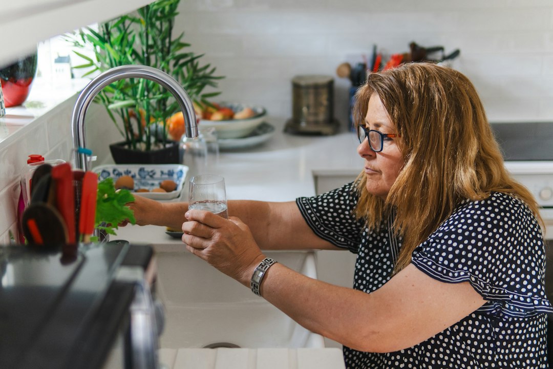 Woman filling a glass of water at a kitchen sink