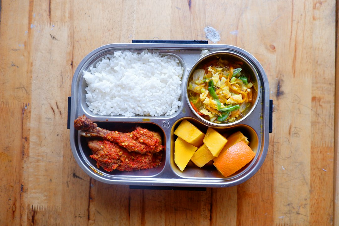A bento box with rice, chicken, eggs, and fruit