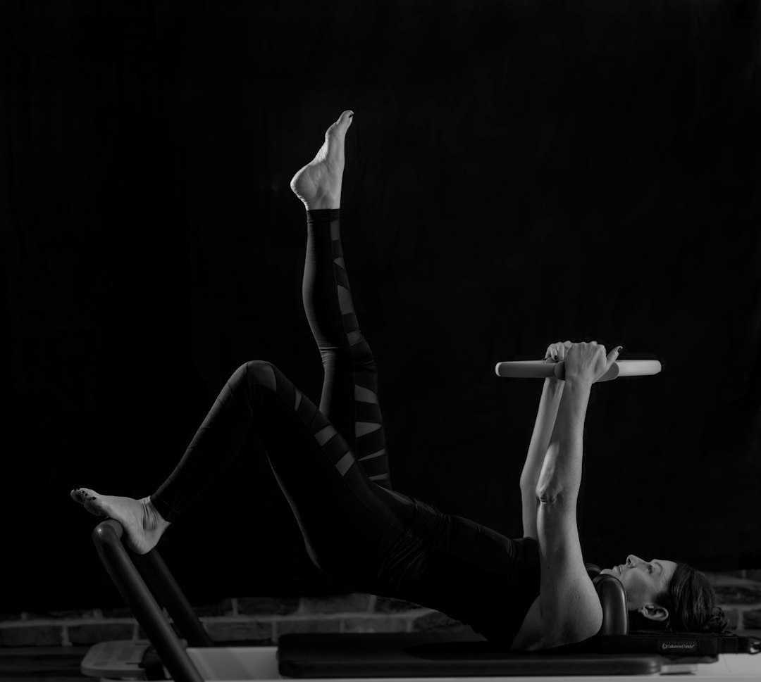 Black and white photo of a woman doing a core exercise on a Pilates reformer