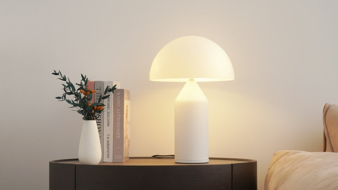 A warm lamp glowing softly on a wooden nightstand in a dim evening room