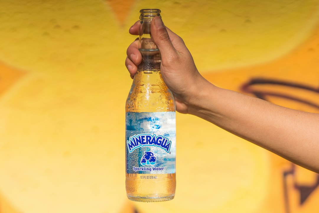 A hand holding a chilled bottle of sparkling water