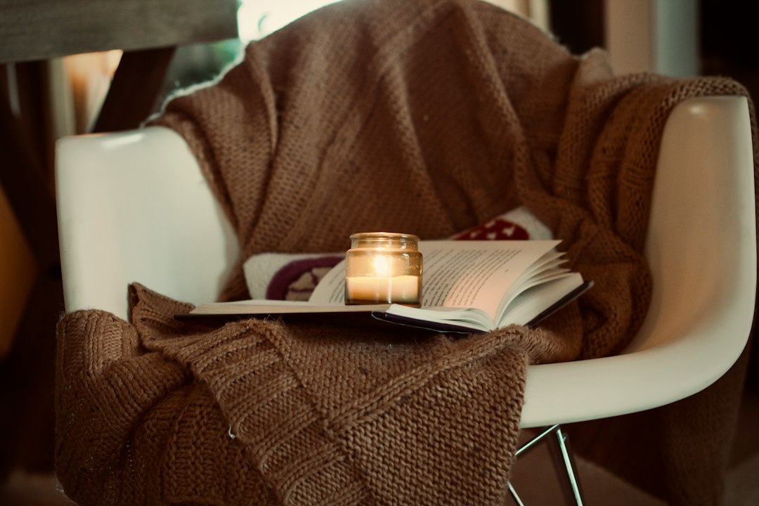 A candle and open book waiting on a cozy chair