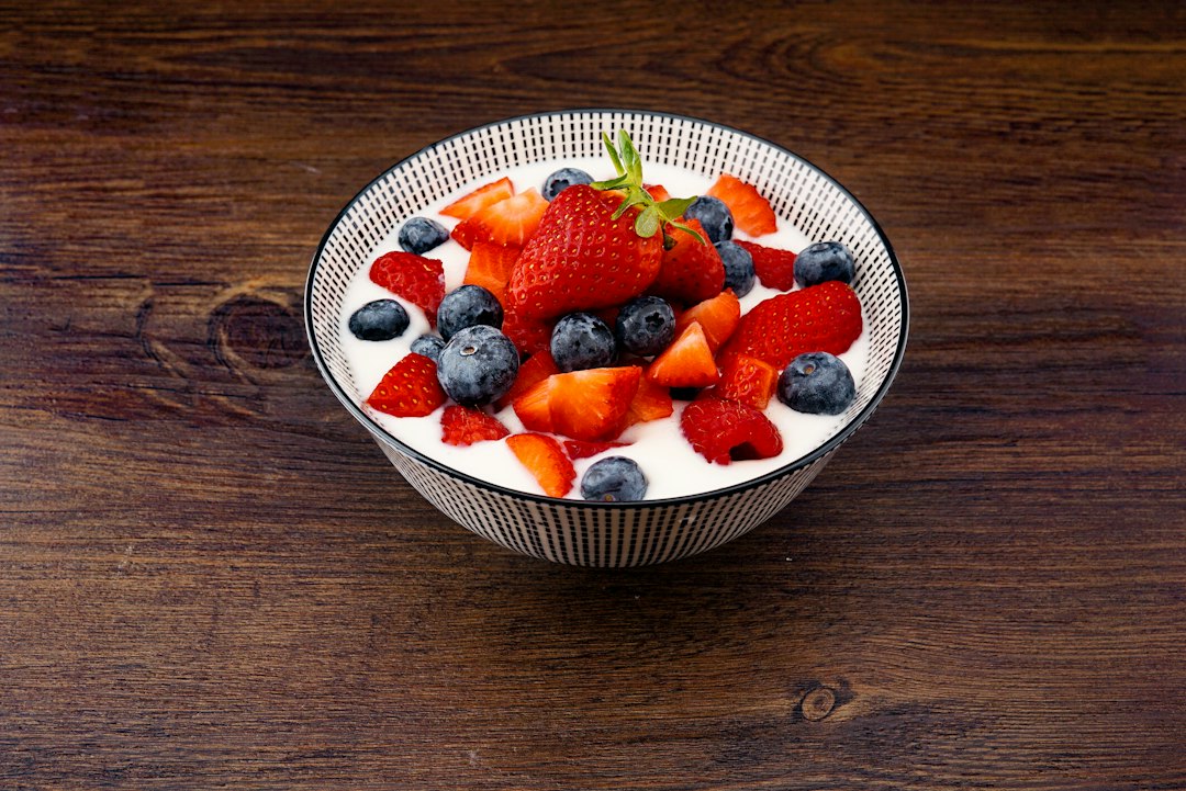 A bowl of yogurt topped with strawberries and blueberries