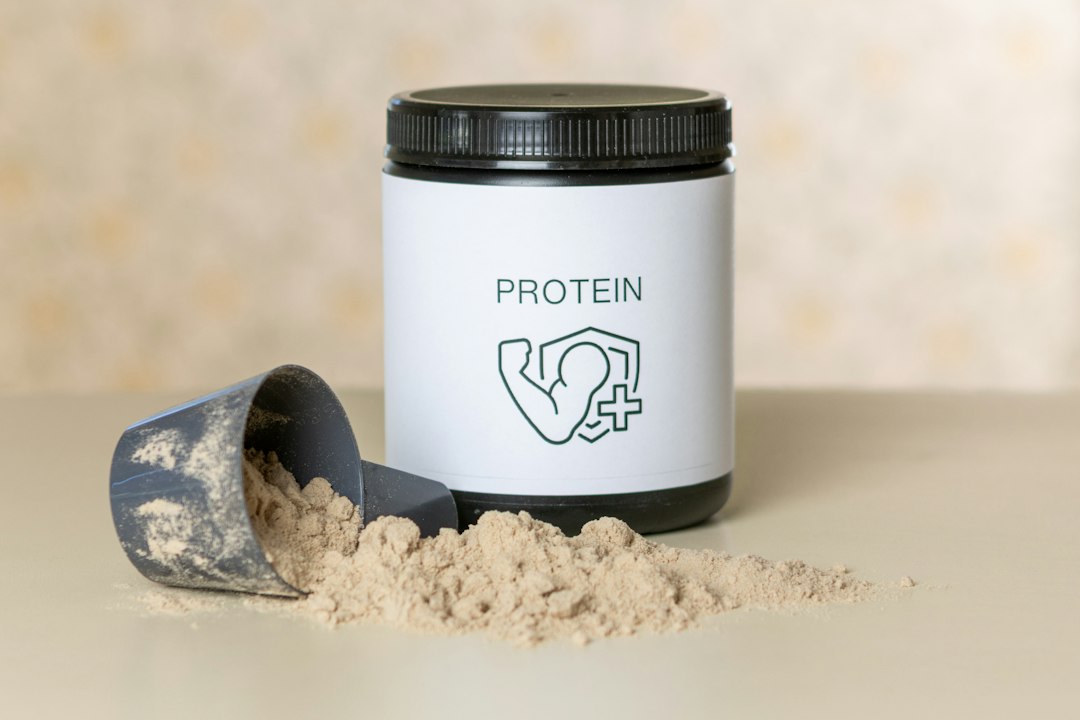An open tub of protein powder with a scoop beside it