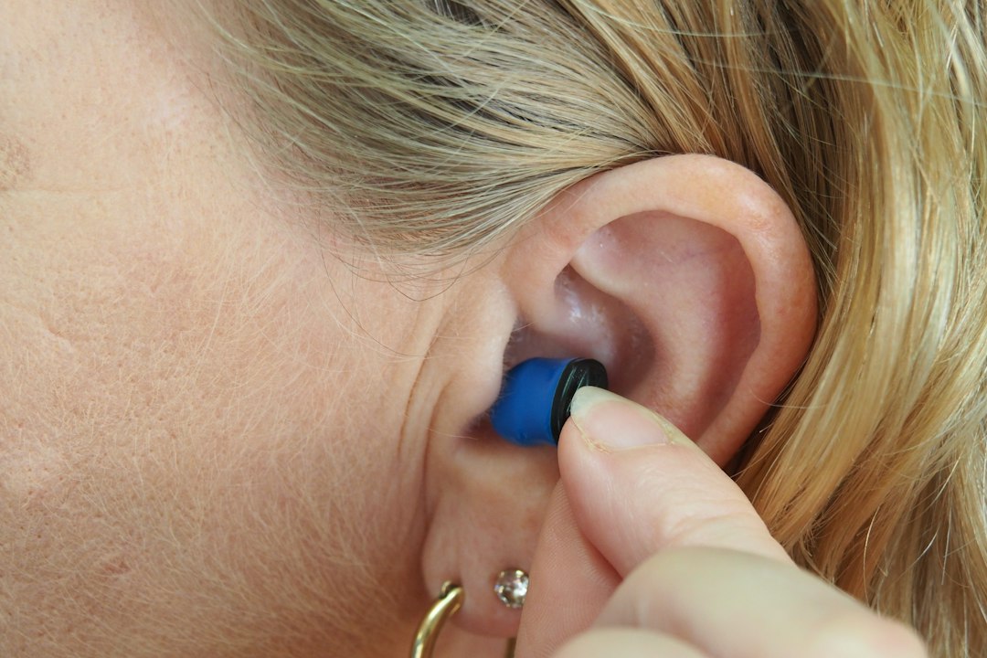 Close-up of a hand inserting a soft blue silicone ear plug